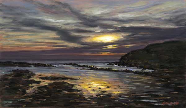 Yellow and red colours of the sun reflect in the sea past a headland